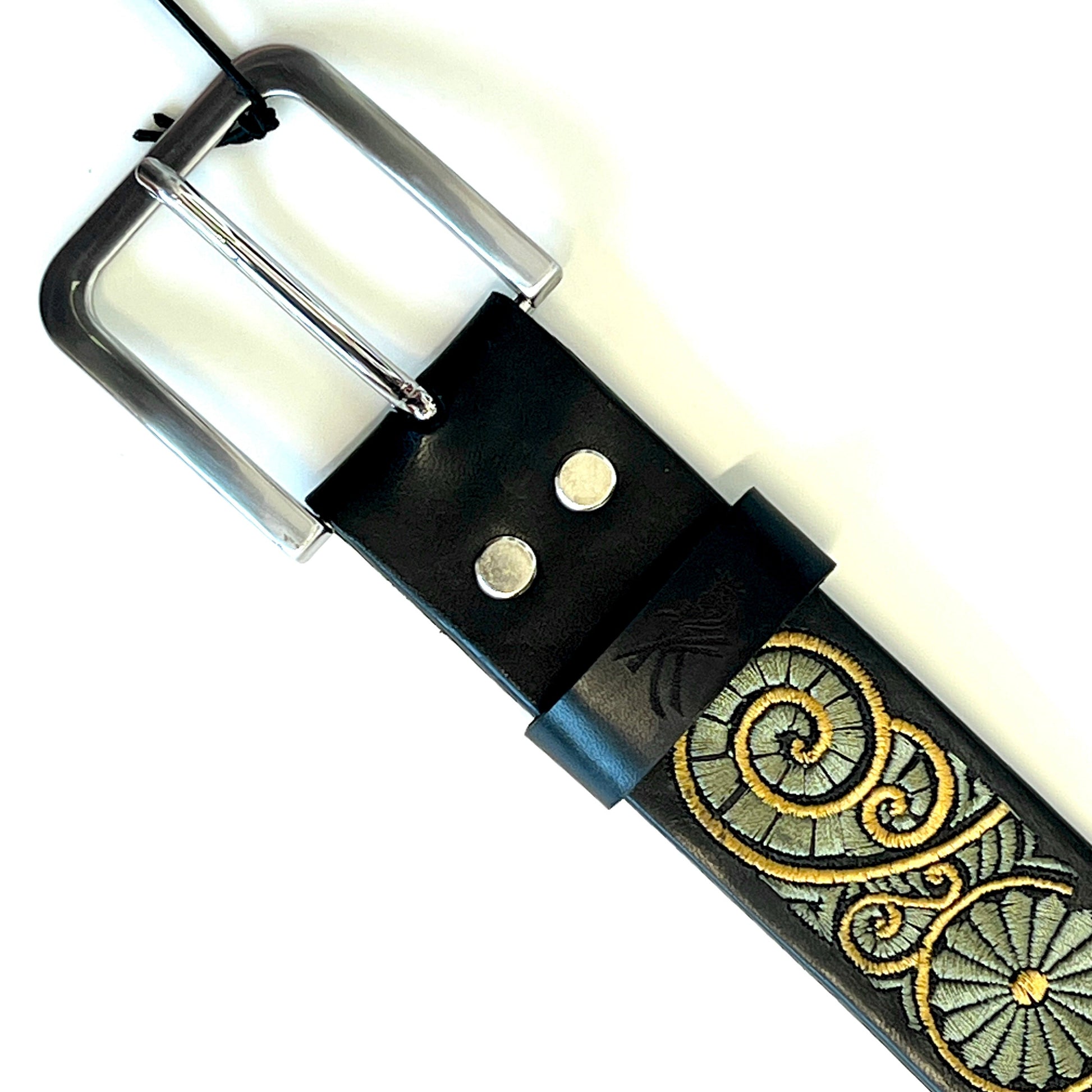 Dettaglio della fibbia della cintura in pelle ricamata con motivo a chiocciola verde e gialla