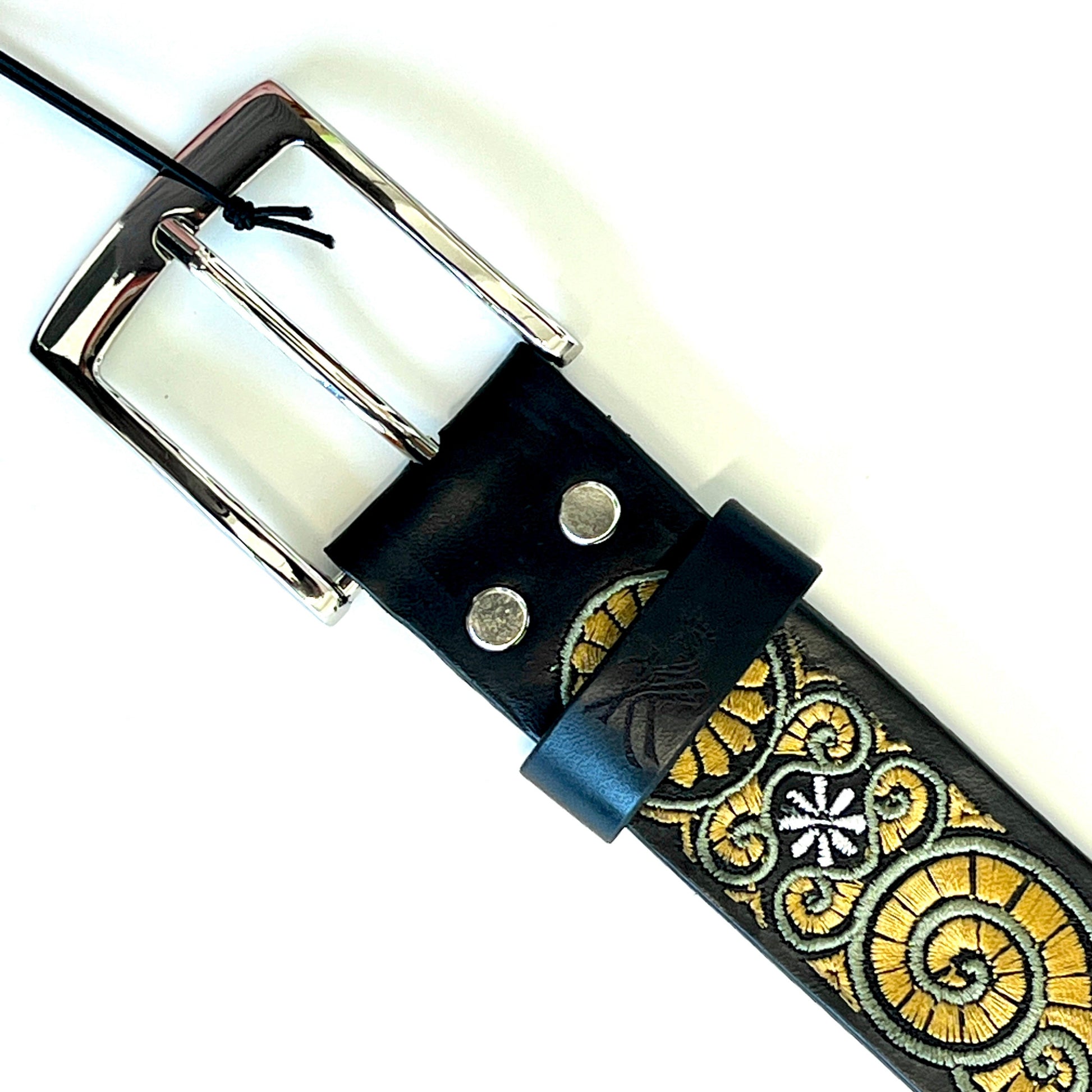 Dettaglio della fibbia della cintura in pelle ricamata con motivo a chiocciola in giallo e verde